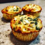 Close-up of three baked Cottage Cheese Egg Cups With Spinach & Feta, showing golden brown tops and visible spinach and feta cheese.