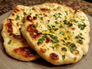 Close-up of two pieces of soft and fluffy garlic naan bread, brushed with melted butter and sprinkled with fresh parsley.