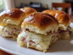 Close-up of delicious ham and cheese sliders with melted cheese oozing out.