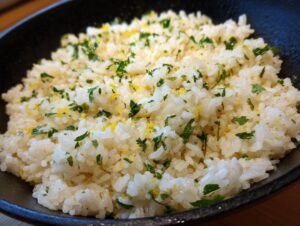 A close-up shot of fluffy Mediterranean lemon rice, garnished with fresh parsley and lemon zest.