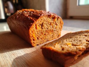 A close-up of a delicious sourdough pumpkin bread loaf with a slice cut and placed in front, showing its moist texture.