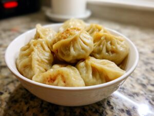 A white bowl filled with freshly made Traditional Chinese Dumplings, lightly seasoned with spices.