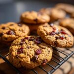 Close-up of freshly baked Cherry Chocolate Mocha Cookies with visible chocolate chips and dried cherries on a cooling rack.