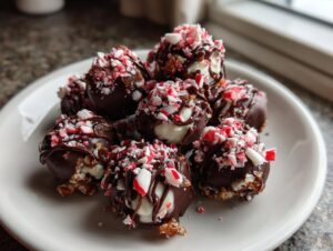 A plate of chocolate-dipped truffles topped with crushed candy canes, perfect for no bake Christmas desserts.