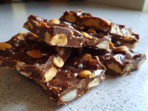Close-up of broken pieces of Crockpot Christmas Crack, a rich chocolate bark studded with peanuts and sprinkled with sea salt.