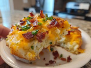 A serving of baked mashed potato casserole topped with melted cheddar cheese, bacon bits, and green onions.