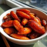 A close-up of sweet, glossy maple brown sugar glazed carrots served in a small white bowl.