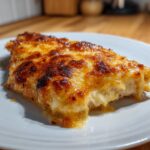 Close-up of a portion of melt in your mouth chicken covered in bubbly, golden-brown baked cheese.