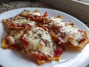 Close-up of several freshly baked pizza chips topped with melted mozzarella, tomato sauce, and dried herbs.