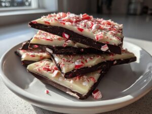 A stack of dark and white chocolate peppermint bark pieces topped with crushed candy canes.