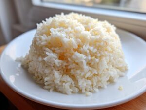 A perfectly molded mound of fluffy, glistening butter rice served on a simple white plate.