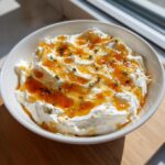 A creamy bowl of homemade ricotta dip topped with golden honey and fresh thyme leaves.