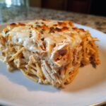 A generous slice of baked Monterey chicken spaghetti topped with melted, browned cheese and herbs.