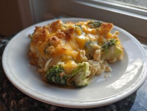 A close-up serving of creamy Chicken Divan topped with melted cheddar cheese and crispy breadcrumbs, featuring bright green broccoli florets.