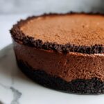 A close-up view of a decadent chocolate mousse pie featuring a thick, dark chocolate mousse layer and a crumbly chocolate crust.