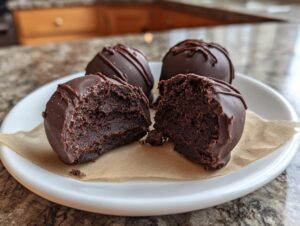 Close-up of chocolate-coated Oreo balls, one cut in half showing the rich, fudgy interior.