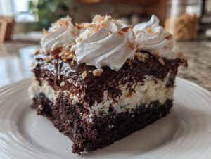 A rich slice of german chocolate poke cake showing layers of dark chocolate cake, white filling, and chocolate topping with whipped cream.
