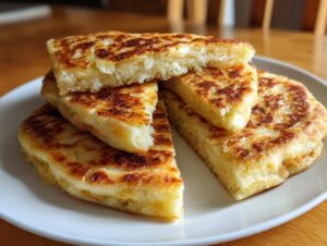 A stack of freshly cooked, golden brown irish potato farls, cut into wedges, showing a fluffy interior.