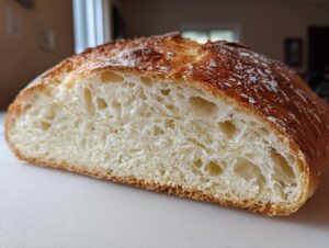 Cross-section view of a freshly baked Italian bread loaf showing a golden crust and an open, airy crumb structure.