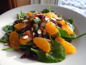 Close-up of a fresh mandarin orange salad featuring spinach leaves, bright orange segments, sliced almonds, and dried cranberries.