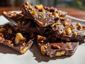 Close-up of broken pieces of rich, dark pecan pie bark topped generously with chopped pecans.