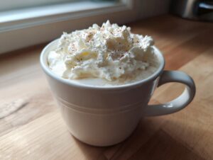 A creamy white hot chocolate topped high with whipped cream and a dusting of cinnamon.