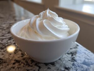 Close-up of stiff, bright white royal icing recipe piped into a small white bowl.