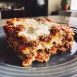 A close-up, appetizing slice of skillet lasagna layered with meat sauce and melted mozzarella cheese.