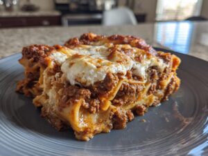 A close-up of a hearty slice of skillet lasagna with layers of meat sauce and creamy ricotta cheese on a gray plate.