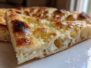Close-up cross-section showing the airy, soft interior and golden, glistening top of homemade naan bread.