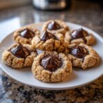 A plate of freshly baked peanut butter blossom cookies with a dollop of shiny, melted chocolate center.