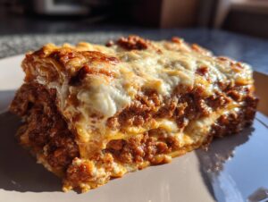 Close-up of a rich, multi-layered slice of lasagna showing meat sauce and melted cheese topping.