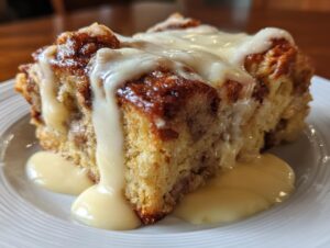 A close-up of a warm, rich slice of bread pudding recipe topped with a thick vanilla glaze.