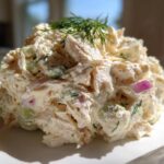 A scoop of creamy cottage cheese chicken salad mixed with celery and red onion, garnished with fresh dill.