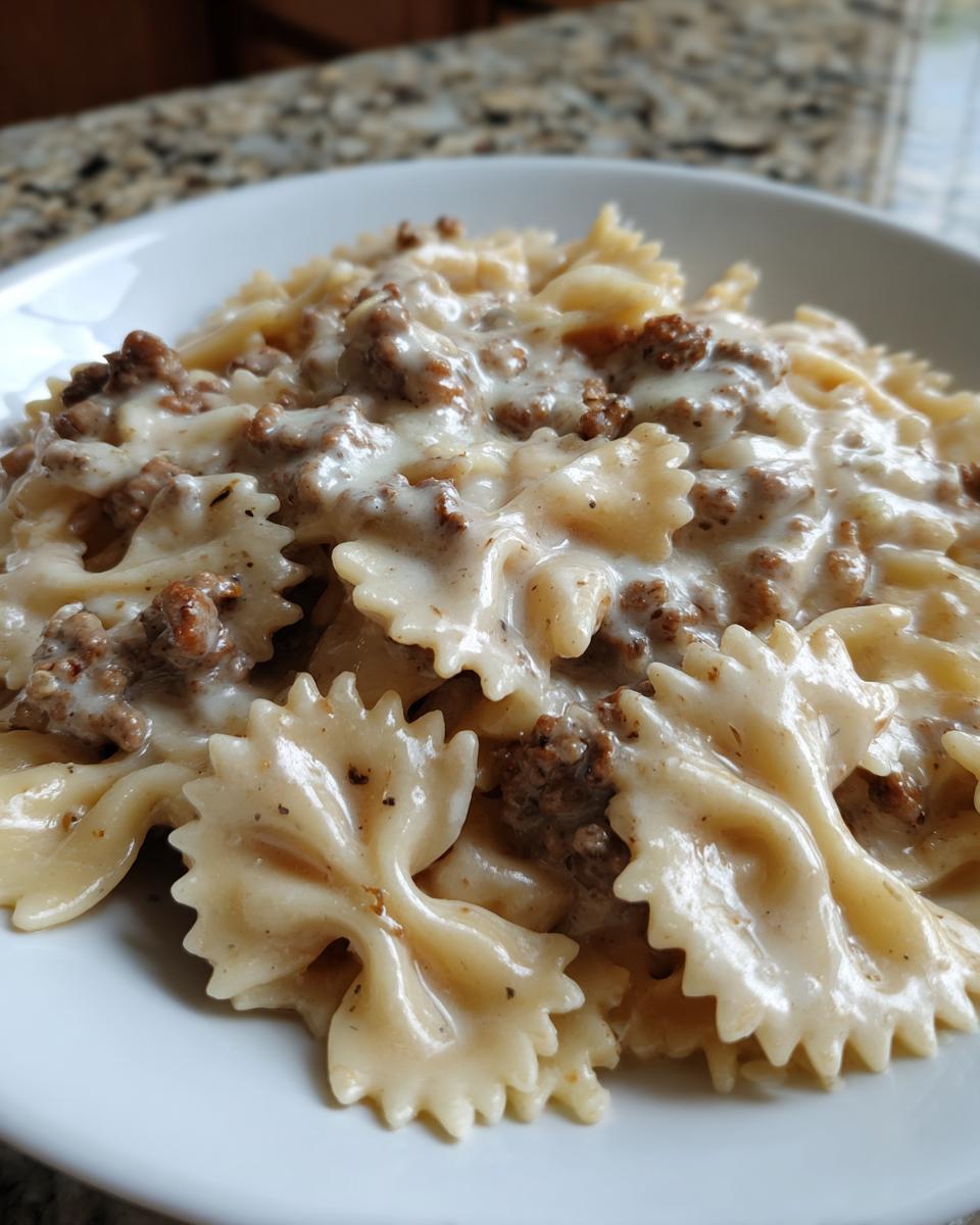 Close-up of bowtie pasta coated in a rich, creamy parmesan garlic sauce with ground beef.