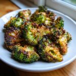 Close-up of perfectly crispy, oven-roasted smashed broccoli florets with browned, cheesy edges.