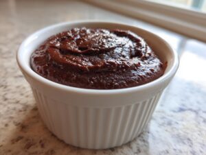 Close-up of thick, rich homemade chocolate pudding served in a white fluted ramekin.