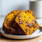 Two moist slices of chocolate chip pumpkin bread served on a small white plate.