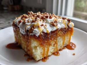 A decadent slice of pumpkin poke cake soaked in caramel, topped with whipped cream and pecans.