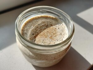 Overhead close-up of creamy chia seed pudding topped with cinnamon in a glass jar.
