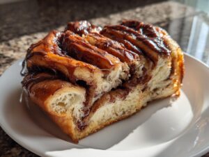 A close-up of a slice of amazing chocolate babka showing its rich, gooey chocolate swirl and soft, layered dough.