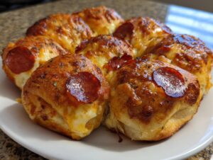 Close-up of freshly baked pepperoni pizza sliders arranged in a circle, featuring melted cheese and golden-brown tops.