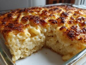 Close-up of a portion removed from a baked mac and cheese recipe, showing creamy interior and deeply browned, bubbly cheese topping.