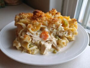 A close-up serving of creamy chicken noodle casserole topped with golden breadcrumbs and melted cheese.
