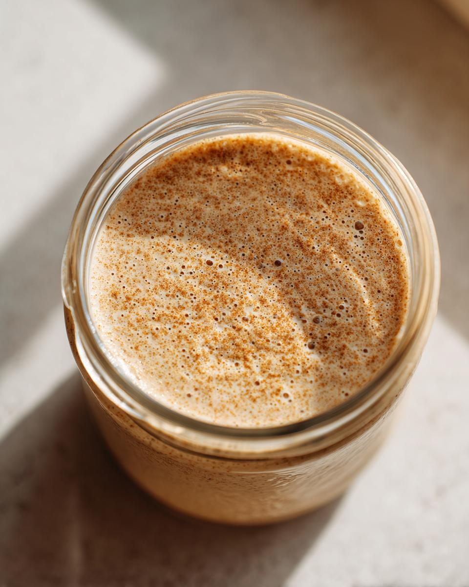 Overhead close-up of creamy chia seed pudding topped with sprinkled cinnamon in a glass jar.