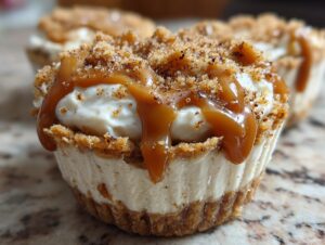 A close-up of one of the amazing cookie butter cheesecake cups topped with thick caramel sauce and cookie crumbs.