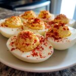 Close-up of deviled egg halves filled with creamy yolk mixture and sprinkled generously with paprika, a perfect egg appetizer.