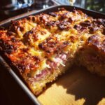 Close-up of a freshly baked homemade reuben bake with a golden, cheesy crust and visible layers of ham inside.