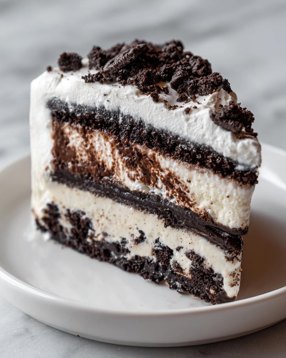 A tall slice of no-bake ice cream cake featuring layers of chocolate cookie crust, vanilla ice cream, and topped with whipped cream and cookie crumbs.