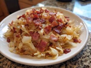 A close-up of a Southern cabbage recipe featuring sautéed, tender cabbage topped generously with crispy, crumbled bacon pieces.